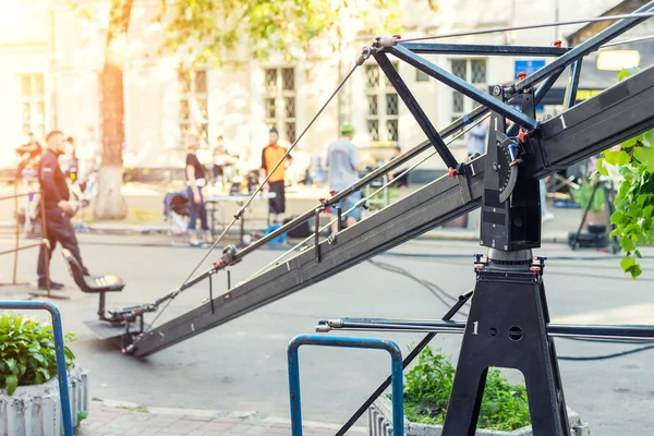 Filmset met professionele apparatuur en media productieteam op City Street. Outdoor film maken. Grote camera kraan met cameraman seat in Open Air Cinema Making scene — Stockfoto