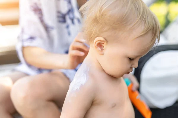 Moeder toepassing zonnebrandcrème bescherming crème op schattige kleine peuter jongen schouder. Mam met behulp van sunblocking lotion om baby te beschermen tegen zon tijdens de zomer zee vakantie. Kinderen Healthcare op reistijd — Stockfoto