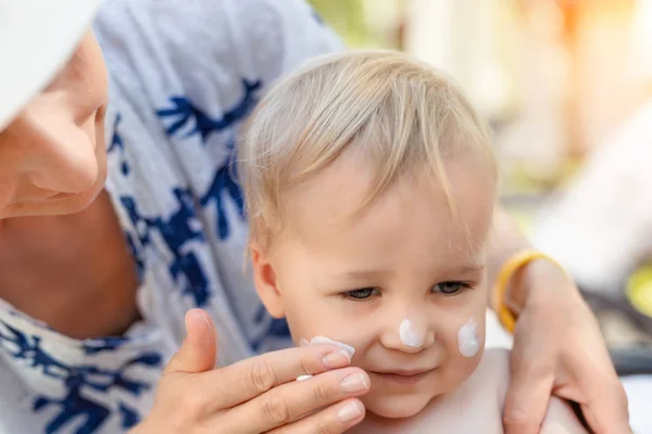 Moeder die zonnebrandcrème aanbrengt op een schattig peutergezichtje. Mam gebruikt zonnebrandcrème om de baby te beschermen tegen de zon tijdens de zomervakantie. Gezondheid van kinderen tijdens reistijd — Stockfoto