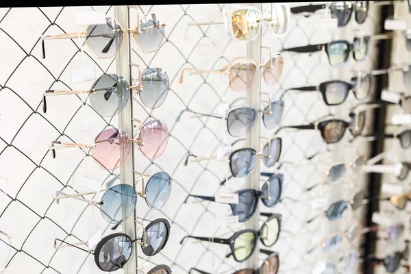 Muitas linhas de óculos de sol na loja de varejo óptico. Escolha rica variedade de diferentes quadros de óculos na exibição da loja de óculos. Proteção UV para caminhada ao ar livre — Fotografia de Stock