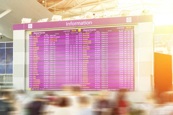 Motion blurred travellers crowd looking at fligh feparture and arrival timetable at airport terminal. Travel and tourism concept. Flight delay — Stock Photo, Image
