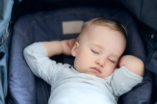 Cute adorable caucasian blond toddler bou sleeping in stroller at daytime. Children healthcare and happy childhood concept — Stock Photo, Image