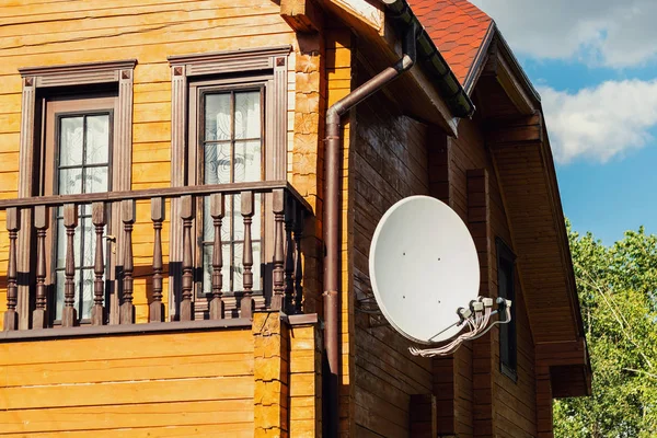 Antena parabólica parabólica branca antena parabólica pendurada na parede da moderna casa de campo de madeira villa. Transmissão de televisão sem fio reciever — Fotografia de Stock