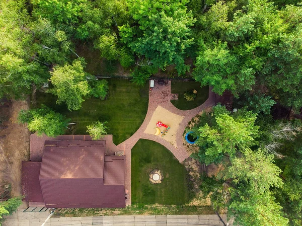 Hermosa casa de madera grande de lujo con patio, parque infantil y caja de arena entre el bosque de árboles verdes. Chalet de madera con césped verde, jardín y zona de barbacoa — Foto de Stock