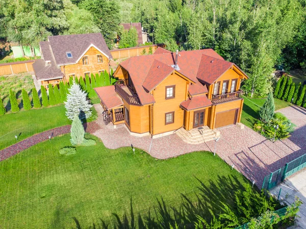 Bella grande casa di legno di lusso. Villetta in legno con prato verde, giardino e cielo azzurro sullo sfondo — Foto Stock