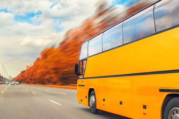 明るい晴れた日に黄金の秋の木の高速道路を運転する大きな豪華な快適な観光バス。ぼやけた動き。旅行とコーチ観光の概念。車でのロードトリップと旅。季節の休暇 — ストック写真