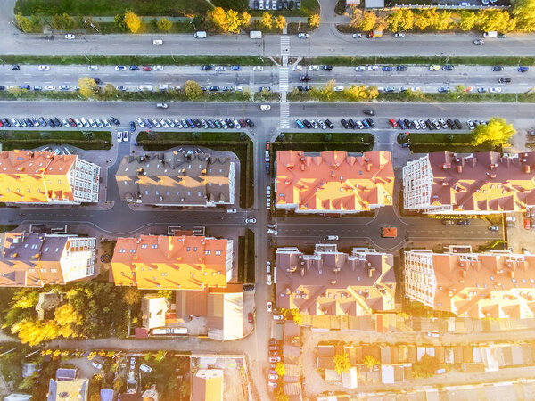 Aerial drone view of residential apartment buildings with driveway road and car parked nearby. City suburbs houses roofs.