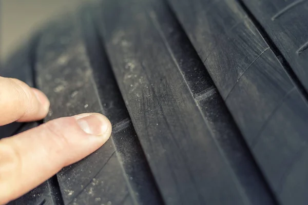 Araç servis merkezinde lastik aşınma göstergesine elle işaret eden mekanik. Bakım sırasında araç tekerlek koruyucu kontrolü ve denetimi