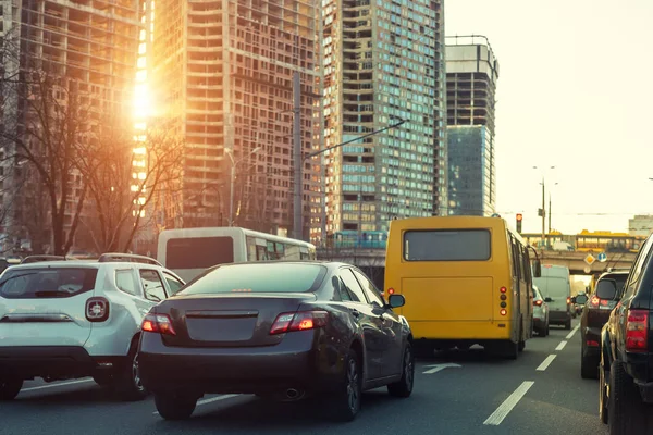 Автомобили на шоссе при пробке города с солнечными лучами заката через Хайтауэр строительной площадки на заднем плане. Вечерняя сцена пик — стоковое фото