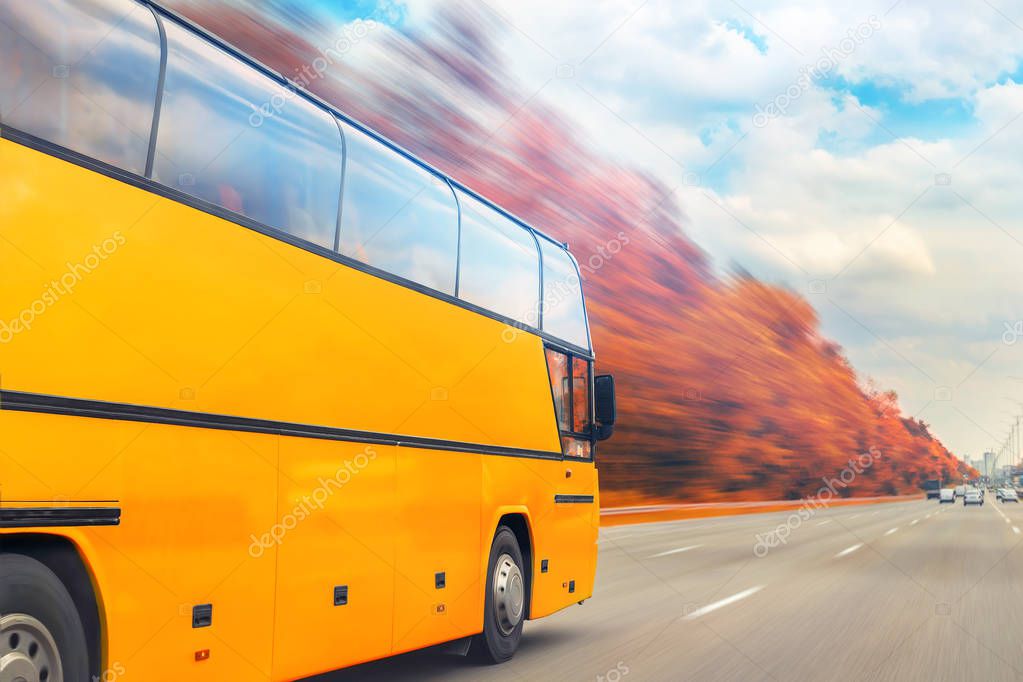 Big luxury comfortable tourist bus driving through golden autumn