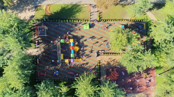 鸟瞰城市公园大现代儿童游乐场之间的树木有很多不同的幻灯片 秋千和娱乐娱乐设备充满了快乐的孩子与父母享受玩游戏 — 图库视频影像