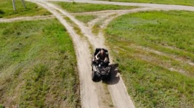 Kuru sonbahar çim ve yeşil kozalaklı ağaç orman çayırları ile ülke engebeli arazi yolu üzerinde bir Atv dört bisiklet sürme genç yetişkin adam Yukarıdan aşağıya havadan görünümü. Macera sporu aktivite konsepti.