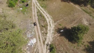 Çevre müfettişinin ya da ATV kuadbike sürerken plastikle kirlenmiş ve diğer farklı çöplerle kirlenmiş bir ormanın içinden yukarıdan aşağı bakışı. Yasadışı atık depolama. Küresel toprak kirliliği sorunu