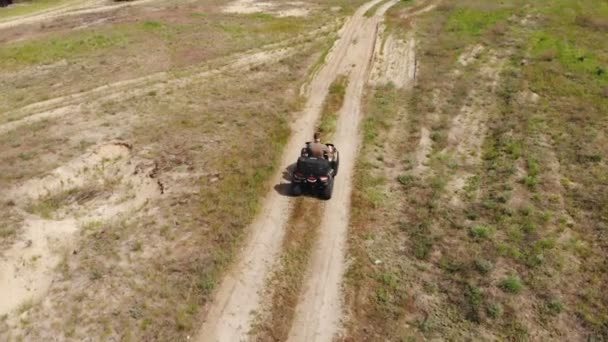 Top-down luchtfoto van jong volwassen man rijden op een ATV Quad fiets over land ruw terrein weg met weiden van droge herfst gras en groene naaldboom bos. Avontuurlijke sportactiviteiten concept — Stockvideo