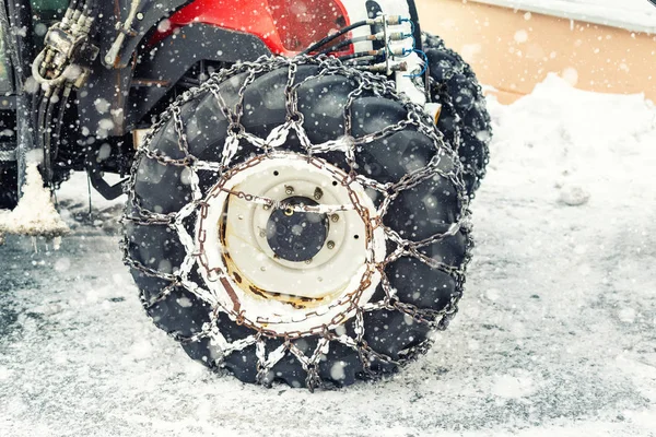 Máquina tractora grande con cadenas metálicas de acero que conducen a través de una carretera helada resbaladiza o calle de la ciudad en la región alpina de la montaña en invierno —  Fotos de Stock