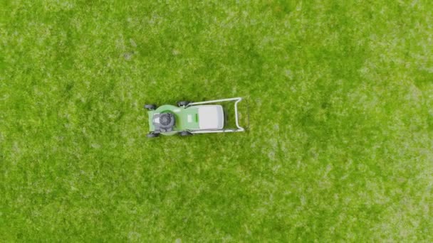 Vista aérea del dron de la cortadora de césped verde en círculo de césped fresco en el patio. Herramientas para cortar hierba. Concepto de servicio de jardinería y equipo — Vídeos de Stock