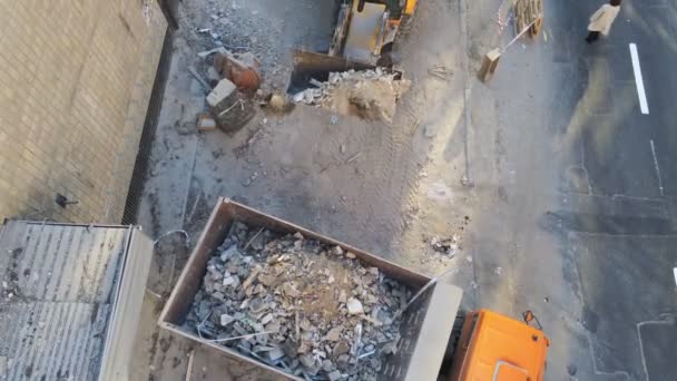 Bulldozer-Lader laden Abfall und Schutt in Kipper auf Baustelle in der Nähe der Straße. Rückbau und Entsorgung von Bauschutt. Industrieller Hintergrund der Drohne aus der Luft — Stockvideo