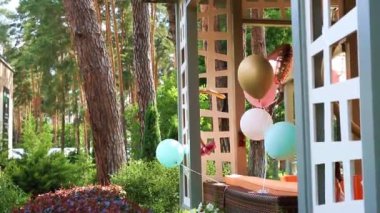 Çocuklar bithday parti için dekorasyon olarak ahşap açık çardak terasbağlı rüzgar oynayan farklı renkli helyum hava balonları Demet. Yıldönümü kutlama dekor tasarımı