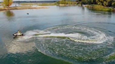 Jet ski sürme ve zümrüt berrak yeşil deniz veya göl suyu üzerinde doğal stunts yapma eğlenceli olan kişinin havadan drone görünümü. Ekstrem yaz sporları aktiviteleri ve seyahat. Tatil tatil macera