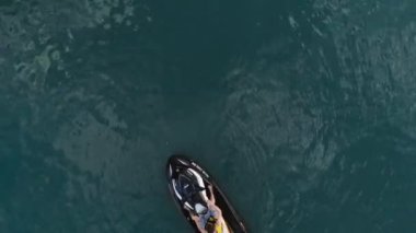Jet ski sürme ve zümrüt berrak yeşil deniz veya göl suyu üzerinde doğal stunts yapma eğlenceli olan kişinin havadan drone görünümü. Ekstrem yaz sporları aktiviteleri ve seyahat. Tatil tatil macera