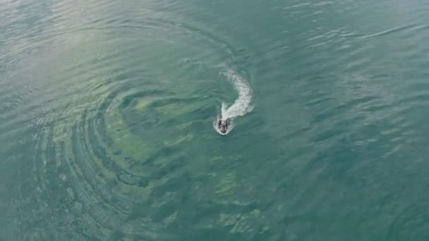 Vista aérea de drones de personas que se divierten montando motos acuáticas y haciendo acrobacias escénicas en el mar verde esmeralda o el agua del lago. Actividades deportivas de verano extremo y viajes. Vacaciones aventura de vacaciones — Vídeo de stock