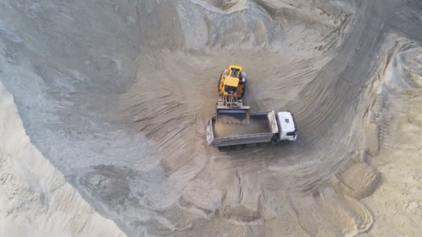 Большой тяжелый колесный погрузчик загружает песок в самосвал в песчаной яме. Концепция тяжелого промышленного оборудования — стоковое видео