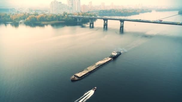 Malerische Luftaufnahme von Kiev und Fluss Dnipro bei Sonnenuntergang. Schlepper stützen Lastkahn mit Sand Schüttgut auf dem Fluss Dnjepr. Ukrainische Binnenschifffahrt und Fracht auf dem Fluss — Stockvideo