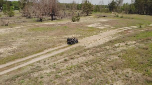 Top-down luchtfoto van jong volwassen man rijden op een ATV Quad fiets over land ruw terrein weg met weiden van droge herfst gras en groene naaldboom bos. Avontuurlijke sportactiviteiten concept — Stockvideo