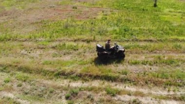 Kuru sonbahar çim ve yeşil kozalaklı ağaç orman çayırları ile ülke engebeli arazi yolu üzerinde bir Atv dört bisiklet sürme genç yetişkin adam Yukarıdan aşağıya havadan görünümü. Macera sporu aktivite konsepti