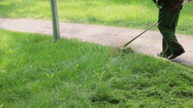 Şehir parkında ya da arka bahçede elektrikli çim biçme makinesiyle çim biçen bir işçi. Bahçıvanlık malzemeleri ve ekipmanlar. Çim biçme makinesiyle çim biçme işlemi