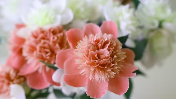 Bukett med färska stora korall rosa, vit och grädde pioner i enkla glasburk på sneans bord inomhus. Vas med vackra ömma våren blommor på glasbord — Stockvideo