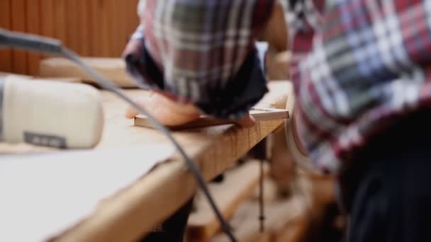 Ανώτερος τεχνίτης άλεση ξύλινο μέρος με μηχανή γυαλόχαρτο στο εργαστήρι ξυλουργικής. Ώριμη Μάστερ στίλβωση λεπτομέρειες του αντικειμένου χειροτεχνίας. DIY οικιακή εργασία — Αρχείο Βίντεο