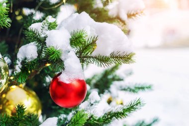 Açık havada kar yağışı sırasında renkli süsleme balosu, kar taneleri ve ladin dallarındaki kar ile yakın plan Noel ağacı. Yeni yıl tatili sezonu konsepti