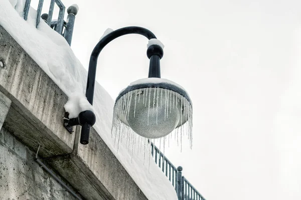 寒冷的冬日，户外街上的灯笼挂在布满冰柱的混凝土墙上。 冬季气候季节背景 — 图库照片