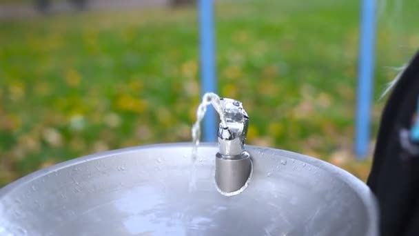 Słodki uroczy biały mały blondyn dziewczyna picia wody z kranu z fontanną wody pitnej w parku miejskim w pobliżu placu zabaw dla dzieci na świeżym powietrzu jesienią. Publiczne zaopatrzenie w wodę pitną dla ludzi — Wideo stockowe