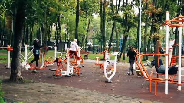 Kiev, Ucrania - 28 de septiembre de 2019: Personas que hacen ejercicios deportivos y entrenamiento en la zona de gimnasio pública al aire libre en el parque de la ciudad. concepto de estilo de vida saludable — Vídeos de Stock