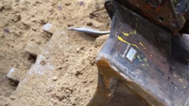 Workers digging and throwing earth with shovel into big steel excavator bucket during hater leak repair or heating pipe liine changing at construction site