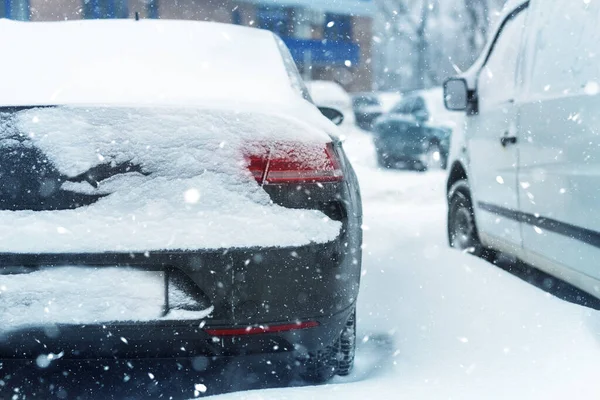Autó parkolt a város utcájában borított vastag hóréteg hóvihar hóvihar idején télen. Járműfarok a hideg téli hóesésnél. Biztonságos vezetés fagyidényben — Stock Fotó