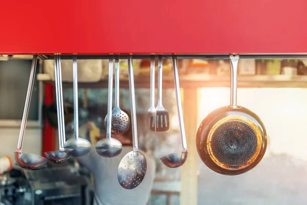 Street food open shop-window with stainless steel set of kitchenware utensils. Blurred chief cook preparing meal on background.Signboard, copyspace