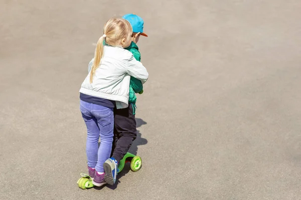 Dois frineds menino e menina se divertindo montando uma scooter juntos simultaneamente. Crianças irmãos, irmão e irmã desfrutando de atividades esportivas ao ar livre — Fotografia de Stock