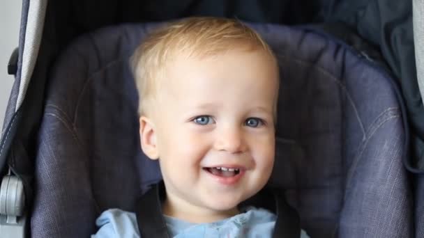 Söt bedårande glad kaukasiska blonda småbarn pojke sitter i barnvagn och skrattar leker söka och dölja spel. Roliga glada barn hänge och visar tungan — Stockvideo