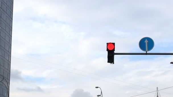 Wechselnde Ampeln und ein rundes Verkehrsschild hingen an einer Säule vor blauem Himmel in der Innenstadt. Erlaubnissignal für Autos und Fahrzeuge — Stockvideo