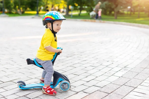 Cute adorable little caucasian toddler boy portrait in helmet having fun riding three-wheeled balance run bike scooter in city park or forest. Child first bike. Kids outdoor sport activities — Stock Photo, Image