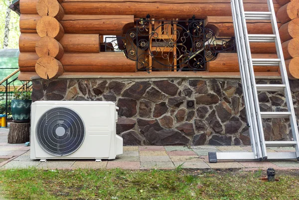 Νέα σύγχρονη HVAC κλιματισμού εξωτερική μονάδα συμπιεστή preapred για εγκατάσταση ή αντικατάσταση κοντά στον τοίχο του ξύλινου log κατοικιών εξοχικό σπίτι. Σκάλα και εξοπλισμός συντήρησης και συντήρησης — Φωτογραφία Αρχείου