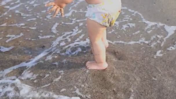 Вид ззаду милий чарівний один маленький кавказький хлопчик-малюк у шортах для плавання, що йдуть через блакитні прозорі водні хвилі тропічного моря або океанського пляжу. Відпустка і подорожі з маленькими дітьми концепція — стокове відео