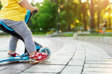 Şehir parkında ya da ormanda üç tekerlekli dengeli motorsiklet sürerken eğlenen sevimli beyaz çocuk. Önce çocuk bisikleti. Çocuklar açık hava sporları aktiviteleri