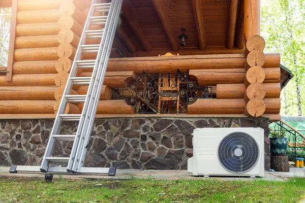 Nova moderna HVAC ar condicionado unidade de compressor externo preapred para instalação ou substituição perto da parede de madeira log casa de campo residencial. Escada e equipamentos para manutenção e manutenção — Fotografia de Stock