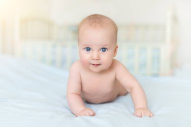 Sevimli, sevimli, beyaz, 5 aylık, bebek bebek bebek bebek, bebek odasında karnının üzerinde uzanıyor, eğleniyor ve gülümsüyor. Yeni doğmuş sağlıklı çocuk konsepti. Komik çocuk, yakın plan portresi.
