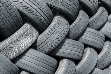 Old used weared car and truck wheels tyres pile stacked in rows stored for recycling. Heap of many rubber tires wall background. Idustrial pollution of environment clipart
