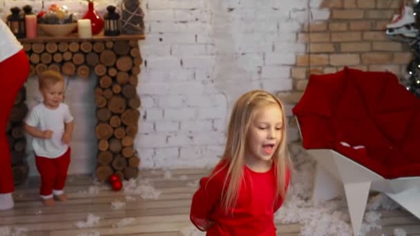 Мила чарівна біла дівчинка в червоному вінтажному ретро-костюмі насолоджується веселими танцями на різдвяній або новорічній вечірці з сім'єю. Забавна дівчинка робить активні енергійні вправи — стокове відео